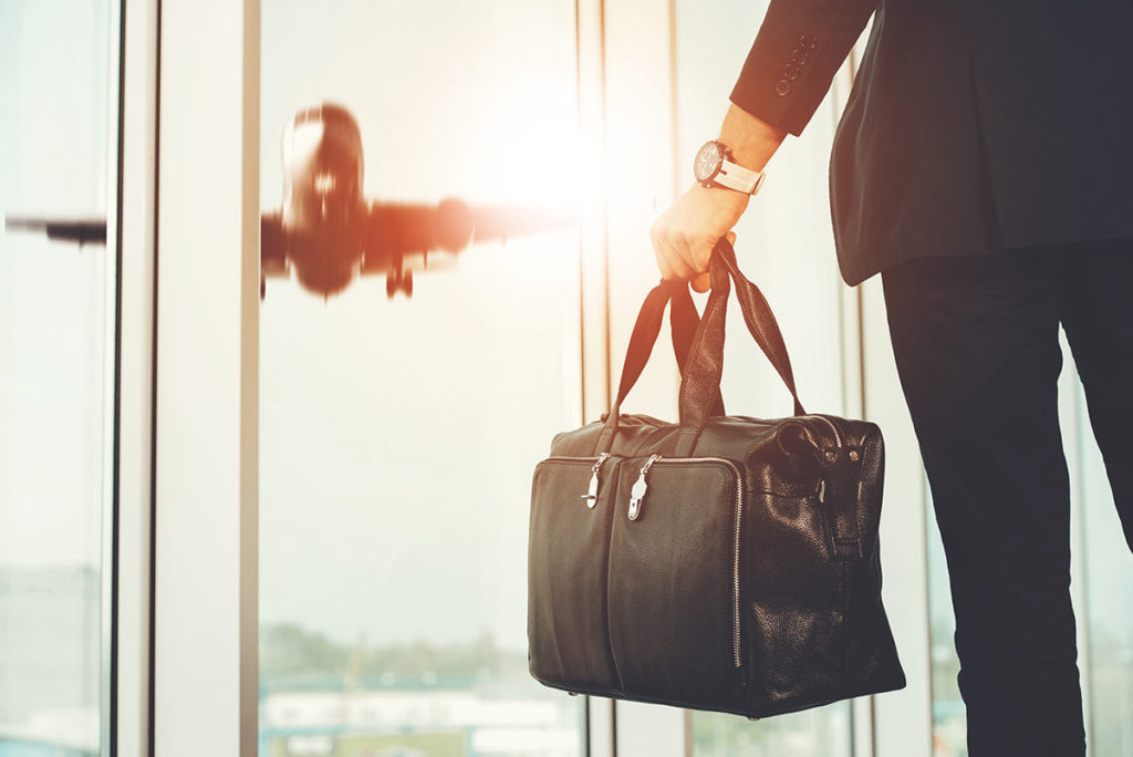 man standing at airport with travel bag in hand